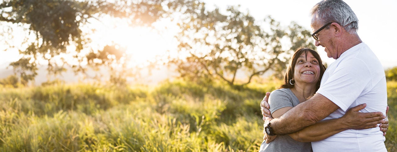 Old couple smiling and holding each other inside the park.