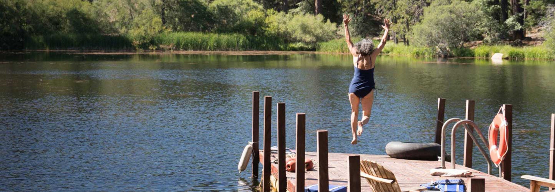 Old woman jumping into lake from the dock.