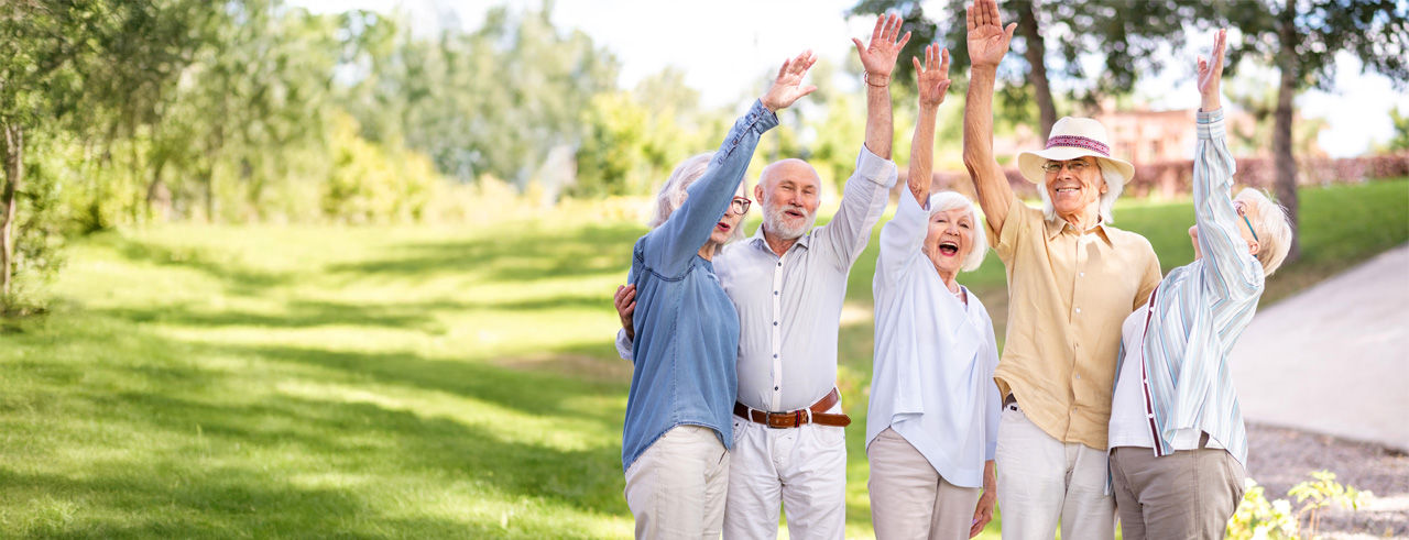 Group of old people inside the pake, smiling and raising one hand in sky.